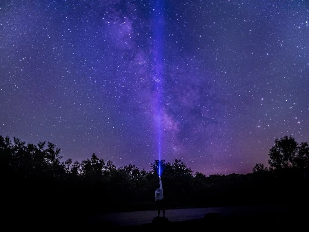Guy shining flashlight into the sky.