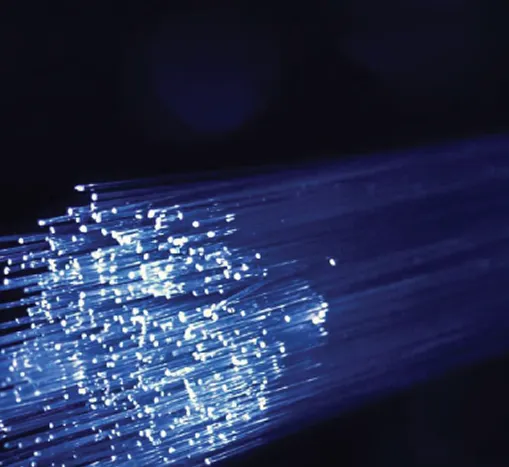 Close-up of glowing fiber optic cables emitting blue light streaks on a dark background