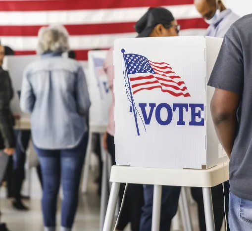 People casting their ballots behind privacy vote boxes